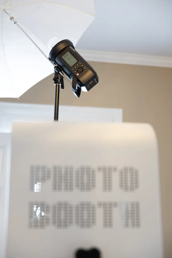 The studio flash mounted high on a stand above the photo booth, firing through a white umbrella
